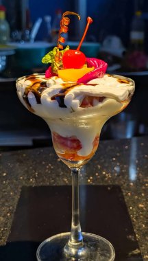 Renkli katmanlı krema, çikolata şurubu, kiraz ve nane aromalı ve uzun bir bardakta zarif bir şekilde servis edilen meyveli parfe..