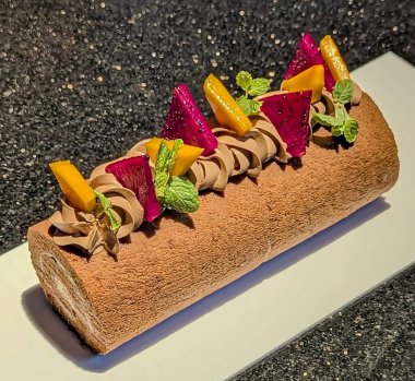 Krem şanti, beyaz çikolata parçaları ve taze nane yapraklarıyla süslenmiş zarif yusufçuk meyveli İsviçre pastası..