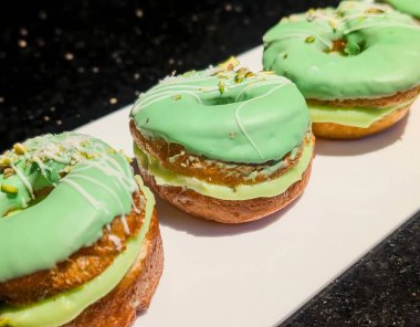 Pürüzsüz şam fıstıklı, yeşil jöleli, beyaz çiselemeli ve ezilmiş fındıklı, kremalı fıstıklı çöreklerin yakın çekimi..