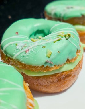 Pürüzsüz şam fıstıklı, yeşil jöleli, beyaz çiselemeli ve ezilmiş fındıklı, kremalı fıstıklı çöreklerin yakın çekimi..