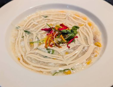 Kremalı çorbanın göz kamaştırıcı bir sunumu, tavuk ve mısırlı yumurta damlası çorbası gibi, karşıt krema veya sosla yaratılmış sanatsal bir girdap tasarımı içeriyor..