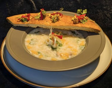 Gevrek, altın sarısı katlanmış, yenilebilir çiçekler ve taze otlarla süslenmiş lezzetli bir yemek..