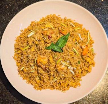 Renkli sebzeler, yumurtalar ve baharatlarla karıştırılmış lezzetli bir porsiyon karides pilavı. Seramik tabakta güzelce şekillendirilmiş..