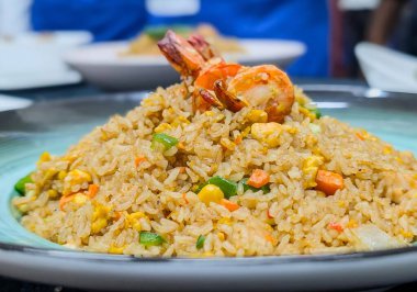 Renkli sebzeler, yumurtalar ve baharatlarla karıştırılmış lezzetli bir porsiyon karides pilavı. Seramik tabakta güzelce şekillendirilmiş..