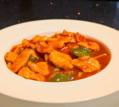 Yeşil dolmalık biberli ve soğanlı portakal soslu taze tavuk parçaları içeren tatlı ve ekşi tavuğun yakın çekimi..