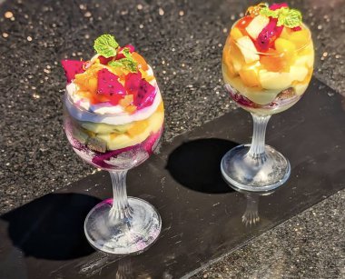 Ejderha meyvesi, mango, kivi ve uzun bir bardakta güzelce servis edilen çırpılmış kremayla kaplı canlı tropikal meyve parfe..