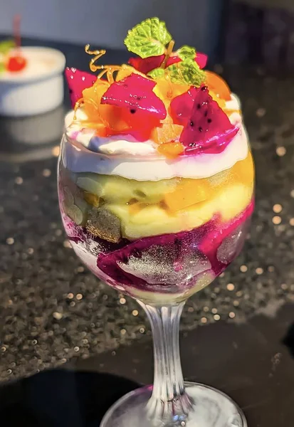 Ejderha meyvesi, mango, kivi ve uzun bir bardakta güzelce servis edilen çırpılmış kremayla kaplı canlı tropikal meyve parfe..