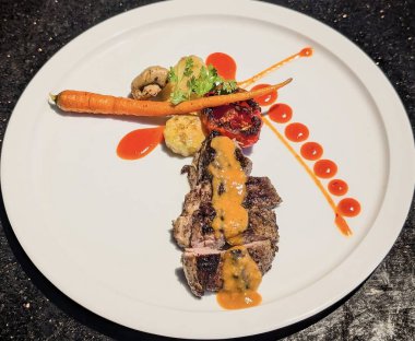 Dilimlenmiş bifteğin çarpıcı bir sunumu, muhtemelen fileto, arzu edilen orta-nadir bir iç mekan ve kömürleşmiş bir dış görünüş, zarif bir şekilde portakal-kahverengi sosla kaplanmış..