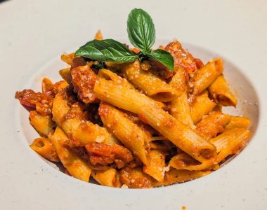 Mükemmel pişirilmiş makarna servisinin davetkâr kişisi cömertçe zengin, tıknaz bir domates sosuyla kaplıdır.