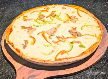 Kalın, kremsi beyaz soslu ya da dilimlenmiş mantarlar ve yeşil ve turuncu kağıt şeritlerle süslenmiş ağır peynirli, lüks bir pizzanın yukarıdan aşağı manzarası..