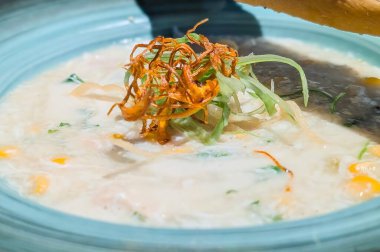 Kızarmış soğan ve iştah açıcı bir son için taze yeşil otlarla kaplı mavi seramik bir kasede sunulan kremalı tavuk çorbası..