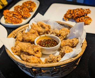 Beyaz parşömen kağıdıyla kaplanmış, kırsal dokuma sepetinde sunulan Asya usulü kızarmış tavuk parçaları..