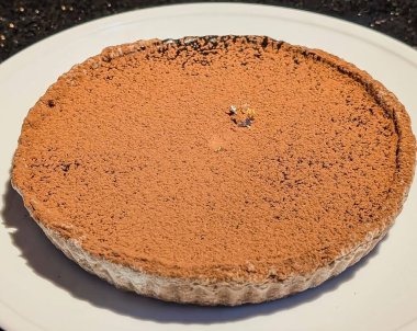 Lüks, zengin bir çikolatalı turta, tamamen kalın, kadife bir kakao tozu tabakasıyla kaplı ve ince bir şekilde yenilebilir altın yaprak parçasıyla süslenmiş..