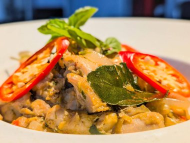 Taze Tayland fesleğeni ve dilimlenmiş kırmızı biberle süslenmiş, bol baharatlı tavuk, soğan ve köri yapraklarından oluşan otantik Tayland usulü kızartma..