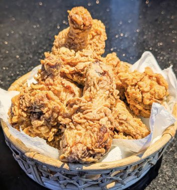 Beyaz parşömen kağıdıyla kaplanmış, kırsal dokuma sepetinde sunulan Asya usulü kızarmış tavuk parçaları..