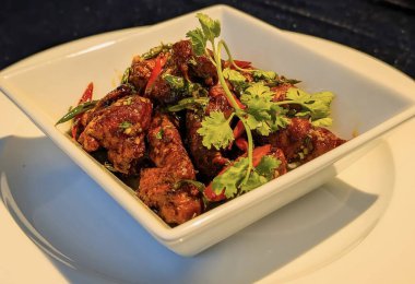 Yakın plan, kıtır kıtır Asya biberli tavuk parçaları, içine tuzlu, tatlı bir sos atılmış ve taze kişniş, kırmızı ve yeşil kırmızı biberlerle süslenmiş..