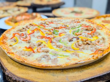 Eritilmiş mozarella, baharatlı et, siyah zeytin, mantar, kırmızı soğan ve renkli dolmalık biberle kaplanmış taze pişmiş, yüce bir pizza..