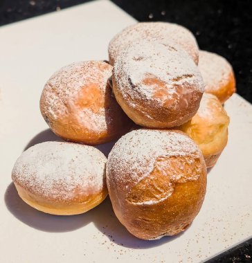 Bir yığın altın esmer reçelli çörek pudra şekerle tozlanmış, temiz beyaz bir yüzeye şekil verilmiş..
