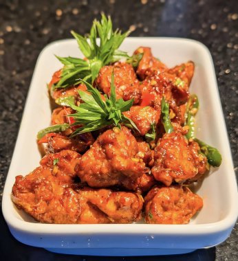 spicy fried chicken garnished with fresh herbs and chili peppers in a white serving dish. Perfect for Asian cuisine, restaurant menus, and street food concepts.