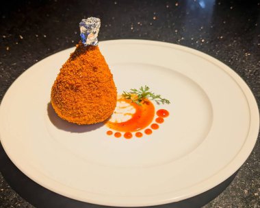 Bol yağda kızartılmış portakal kaplamalı konilerin sanatsal sunumu. Kremalı pembe-turuncu sosla doldurulmuş kadehlerin içinde baş aşağı servis ediliyor..