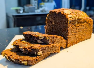 Çikolata parçacıklarıyla süslenmiş, nemli, hassas kırıntılarını ve derin kakao dokusunu ortaya çıkarmak için dilimlenmiş zengin bir çikolatalı ekmek..