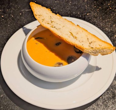 Bir kase kremalı çedar mantarı çorbası üzerine sotelenmiş mantar ve kızarmış otla eşleştirilmiş.