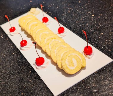 Dilimlenmiş sarı İsviçre usulü kremalı pasta, krem şanti ve vişne ile süslenmiş..