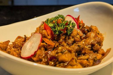 Kırmızı biber dilimleri, turp, sarımsak ve taze maydanozla süslenmiş soya soslu tuzlu tavuk parçaları..