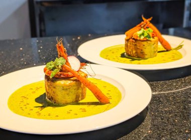 Üzerine ızgara karides, kızarmış havuç ve taze nane yaprakları ile kaplanmış canlı yeşil bitki sosuyla kaplı zarif bir kaplama terrine..