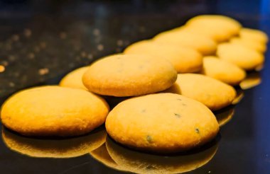 Orijinal Hint Nankhatai kurabiyeleri dilimlenmiş şam fıstığı ve bademlerle süslenmiş parlak siyah bir tepside sunuluyor..