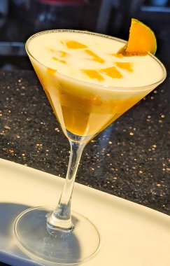 Martini bardağında servis edilen zarif mango kremalı tatlı. Katmanlı sarı püre ve kremalı beyaz yoğurt ve taze mango parçaları..