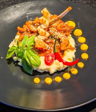 Lezzetli et güveci, susam tohumları, mikro yeşillikler ve dekoratif bir şiş ile süslenmiş patates püresi içeren sanat tabağı..