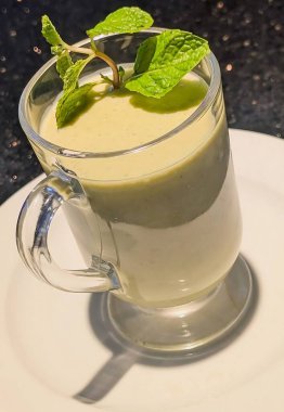 Nane şekeri ve sütle yapılmış, beyaz bir tabakta cam bardakta servis edilen naneli bir smoothie..