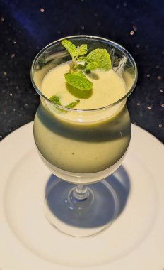 Nane şekeri ve sütle yapılmış, beyaz bir tabakta cam bardakta servis edilen naneli bir smoothie..