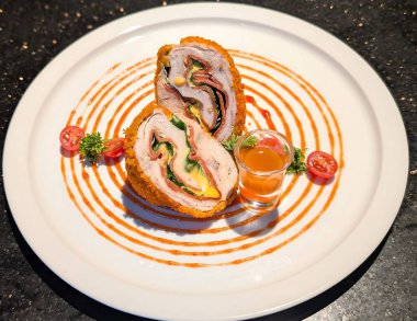 Et, peynir ve ıspanak ile doldurulmuş ruloda rengarenk bir kırmızı sos ve beyaz bir tabakta tamamlayıcı sosla kaplı bir kaplama bulunur..