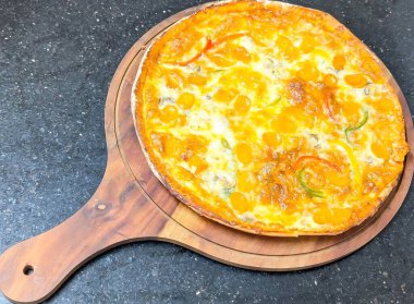 Eritilmiş mozzarella, pepperoni, siyah zeytin ve yeşil ve sarı dolma biberli ahşap bir tahtada servis edilen ahşap üzerine ahşap kaplı pizza..