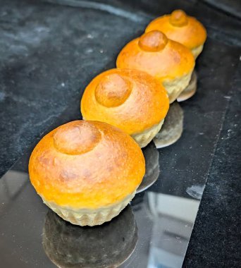 Geleneksel brioche tte hamur işleri parlak altın kabuklar ve yumuşak tereyağlı kırıntılar yansıtıcı siyah bir yüzey üzerinde sunulur.