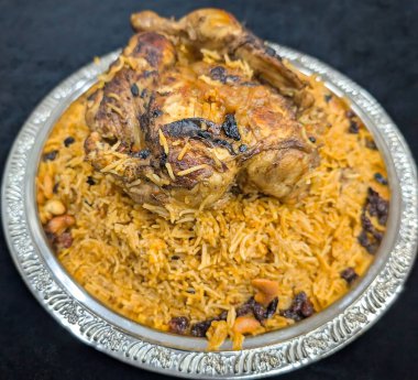 Süslü gümüş çerçeveli tabakta servis edilen kızarmış tavuk biryani ve basmati pilavı, kaju ve kuru üzüm..