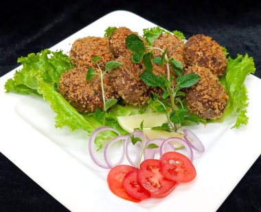 Kıtır kıtır ekmek kırıntılarıyla kaplanmış taze yeşil kıvırcık salatayla servis edilen altın kızarmış et pirzolaları..