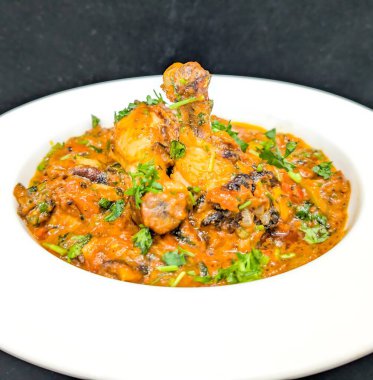 İçinde canlı bir domates ve baharat sosu, doğranmış kişniş ve aromatik baharatlarla süslenmiş iki baget soslu bir tavuk..