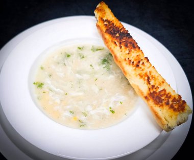 Yumurta çorbası, ipeksi yumurta kurdelesi ve kızarmış sarımsaklı ekmek. Tazelik için doğranmış bitkilerle birlikte..