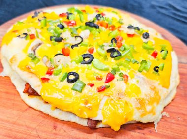 Eritilmiş peynirli, siyah zeytinli, yeşil biberli, kırmızı biberli, mantarlı ve doğranmış yeşil soğanlı ev yapımı vejetaryen pizza..