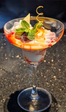 Kremalı vanilyalı krema katılmış gurme çilekli parfe, meyve ezmesi ve kek parçaları, üzerinde gofret çubuğu, nane ve altın şekerli tüy..