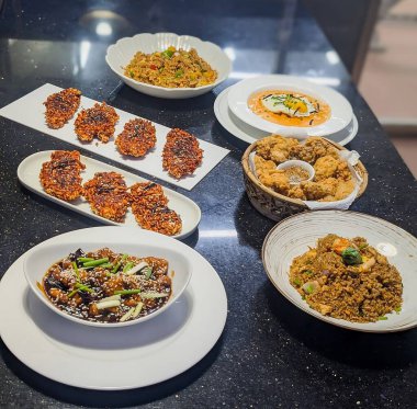 İçinde çıtır erişteli börek, kızarmış tavuk ve beyaz tabakta sunulan sebzeli pilav ve dokuma sepetinin bulunduğu Asya sokak yemekleri tabağı..