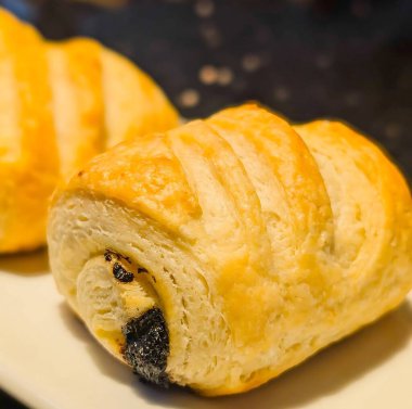 Koyu çikolata dolgulu acı au chocolat hamur işleri ve tereyağlı puf börekleri dikdörtgen beyaz servis tabağında düzgün bir sıraya dizilir..