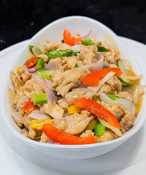 Çan biberi, soğan ve yeşil soğanlı rengarenk tavuk kızartması. Parlak, lezzetli bir sosla servis ediliyor. Aynı tabakta beyaz bir kasede servis ediliyor..