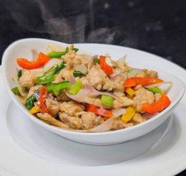 Çan biberi, soğan ve yeşil soğanlı rengarenk tavuk kızartması. Parlak, lezzetli bir sosla servis ediliyor. Aynı tabakta beyaz bir kasede servis ediliyor..