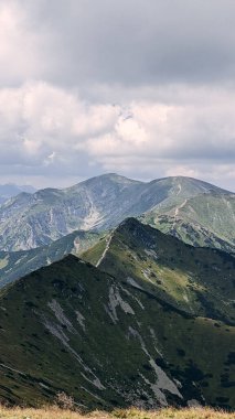Yaz sonunda bulutlu bir gökyüzünün altında manzaralı yürüyüş patikaları olan dağ tepeleri..