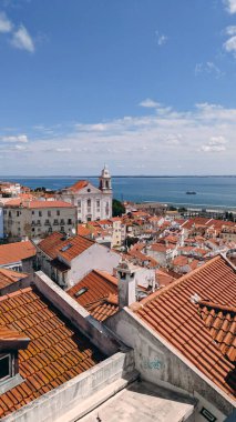 Portekiz, Lizbon 'daki Alfama ve Saint Stephen Kilisesi' ne Tagus nehri ve açık bir gökyüzünün altında feribot manzarası.