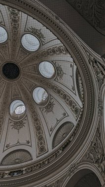 Yuvarlak pencereli kubbeli tavan, barok süslemeler ve aşağıdan görünen karmaşık mimari detaylar.